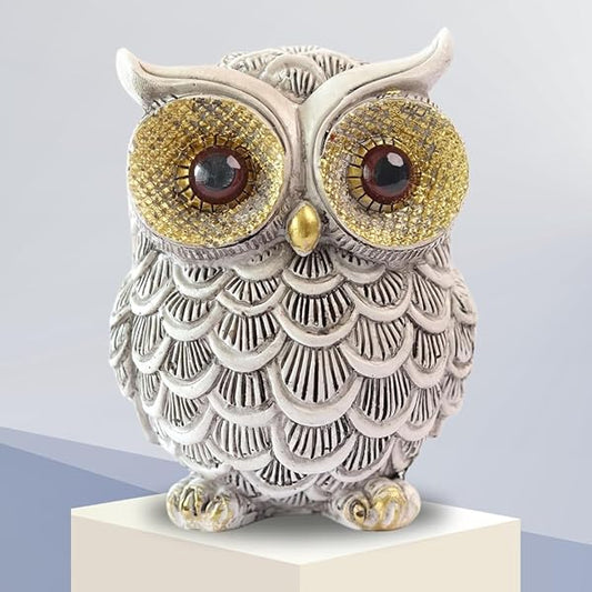 Decorative owl figurine with large eyes on a white pedestal against a light gray background