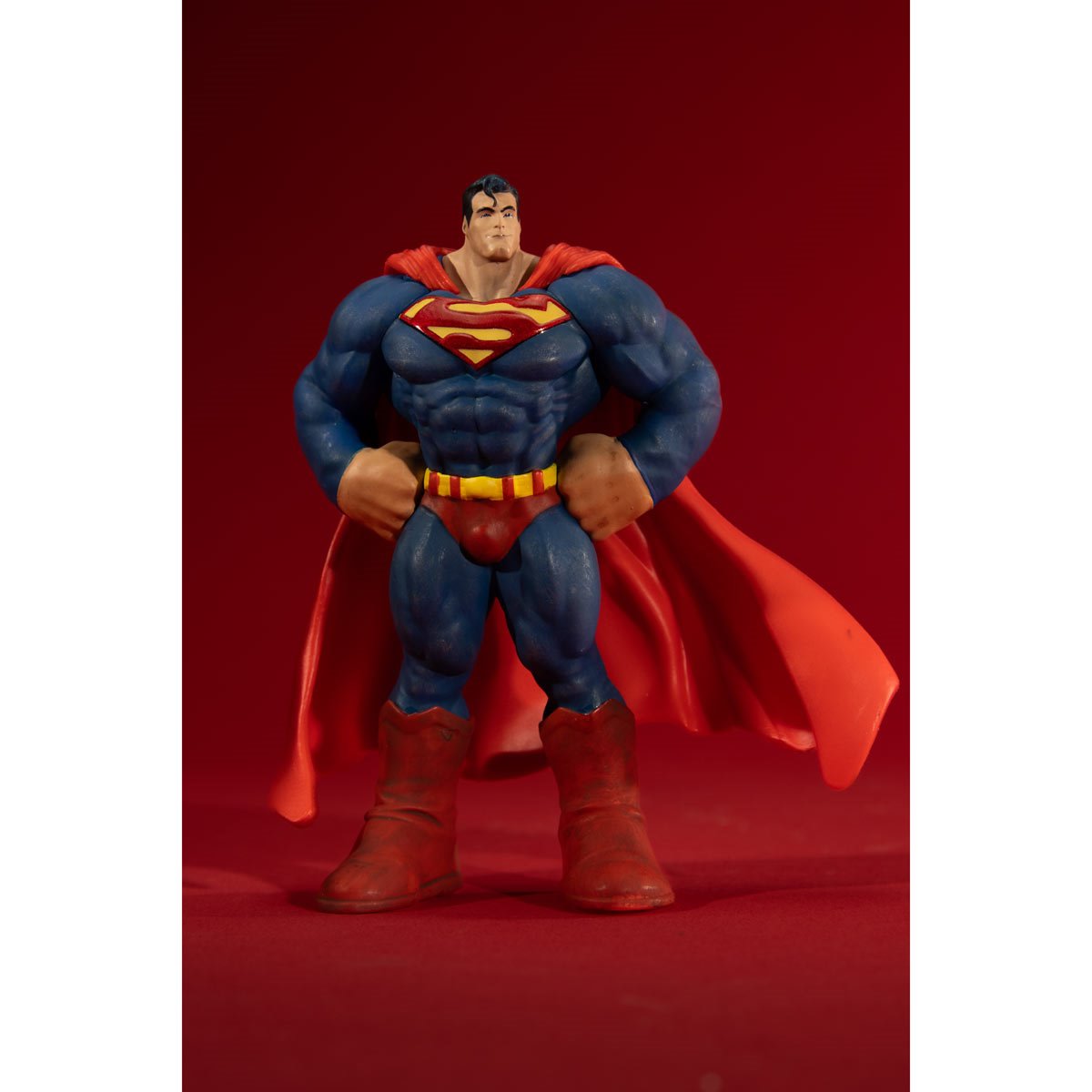 Superman action figure with red cape and blue suit on a red background